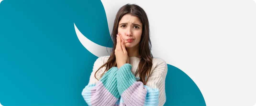 Mulher segurando a boca com expressão de dor causada por sensibilidade dentária.